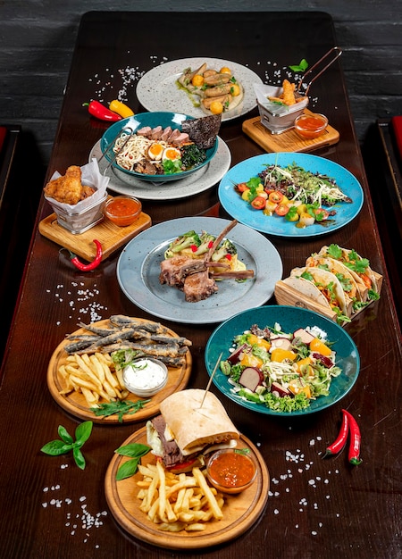 Photo différents repas colorés sur une table en bois sombre dans le restaurant