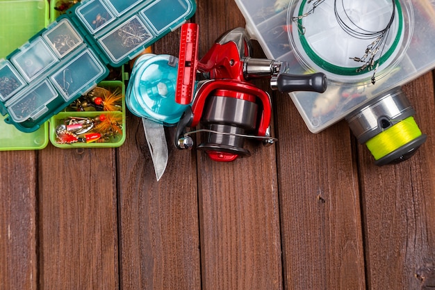 Photo différents tacles de pêche avec leurres et moulinets sur fond brun en bois avec place pour le texte. conception pour la publicité et l'édition.