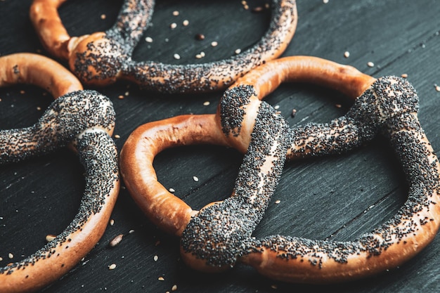 Différents types de bretzels cuits au four avec des graines sur fond noir