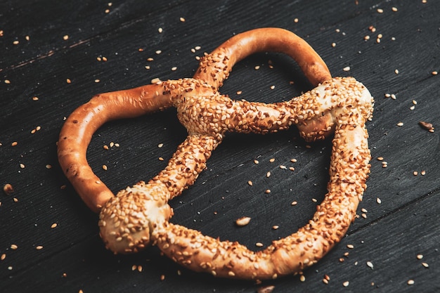 Photo différents types de bretzels cuits au four avec des graines sur fond noir