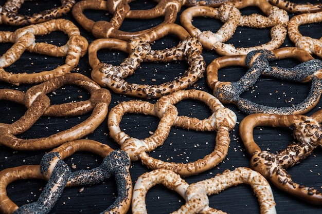 Différents types de bretzels cuits au four avec des graines sur fond noir