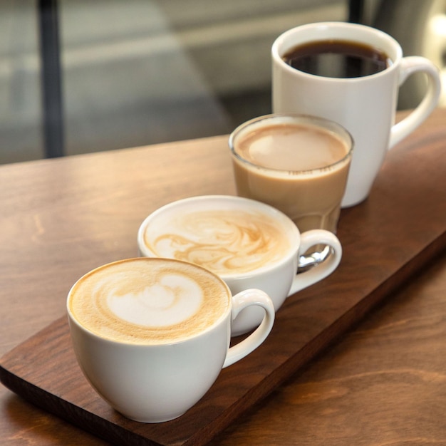 Différents types de café dans des tasses sur un fond de bois cappuccino americano latte macchiato