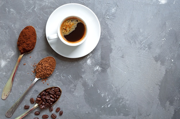 Différents types de café. Grains de café, café moulu et instantané dans les cuillères et une tasse d'espresso frais. Vue de dessus, copiez l'espace.