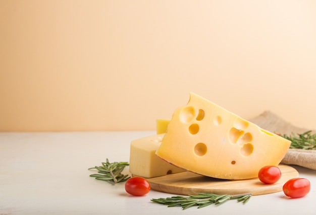 Différents types de fromage au romarin et tomates sur planche de bois sur fond blanc. Vue latérale, espace copie.