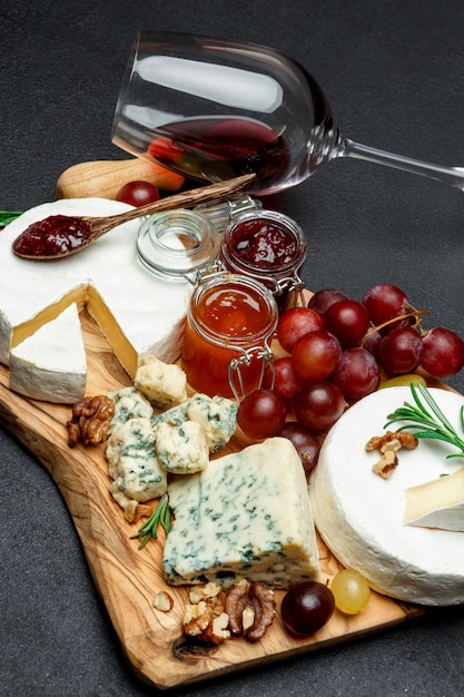 Différents types de fromage, confiture et vin sur une planche à découper en bois