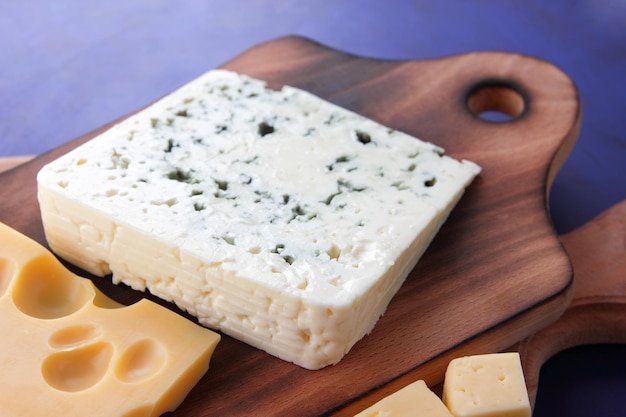 Différents types de fromages sur fond bleu gros plan Fromage bleu et fromage à pâte dure jaune sur planches de bois