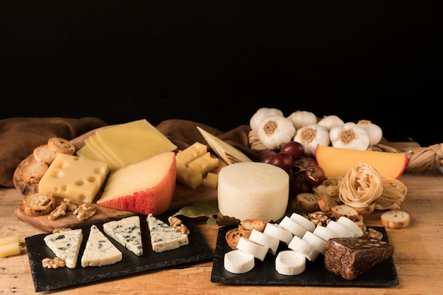 Différents types de fromages s&#39;organisent en pierre d&#39;ardoise sur une table en bois