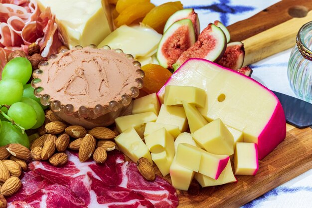 Différents types de fromages, vins, baguettes, fruits et snacks sur la table pour une dégustation et un décor de vacances.