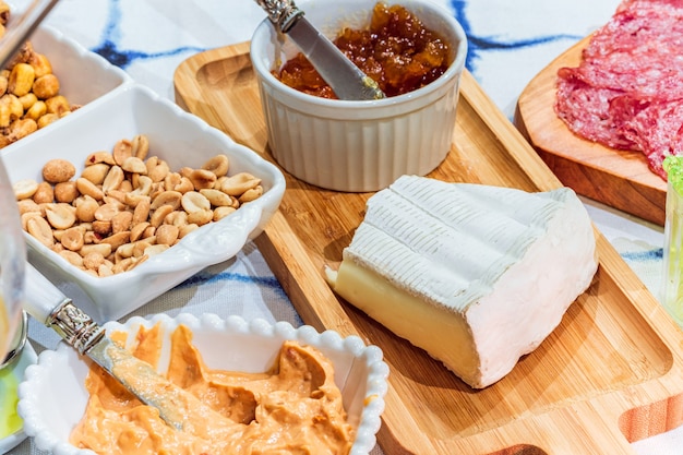 Différents types de fromages, vins, baguettes, fruits et snacks sur la table pour une dégustation et un décor de vacances.