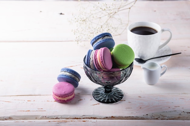 Différents types de macarons dans un vase en verre sur fond de bois clair