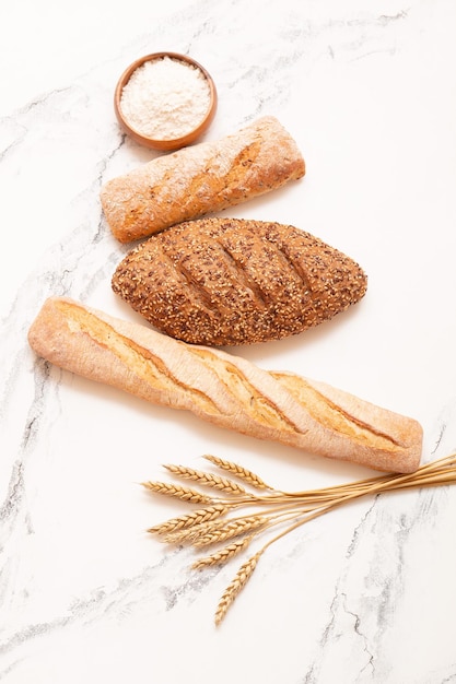 Différents types de pain avec du blé et de la farine sur fond clair