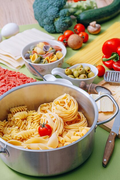 Différents types de pâtes italiennes sur fond de bois avec divers ingrédients pour cuisiner des plats italiens traditionnels