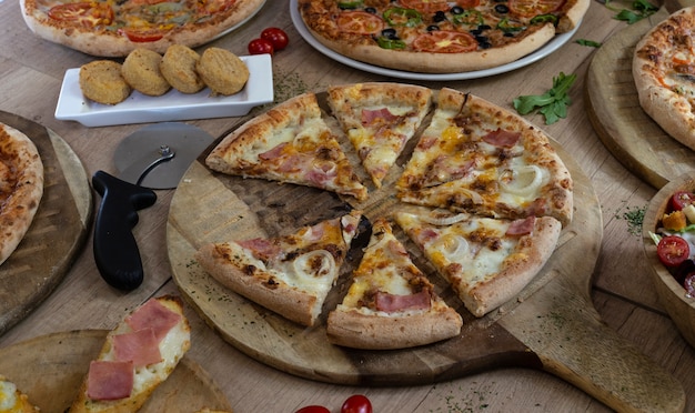 Différents types de pizzas savoureuses sur fond en bois.