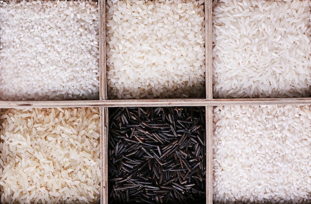 Différents types de riz en boîte sur fond de bois