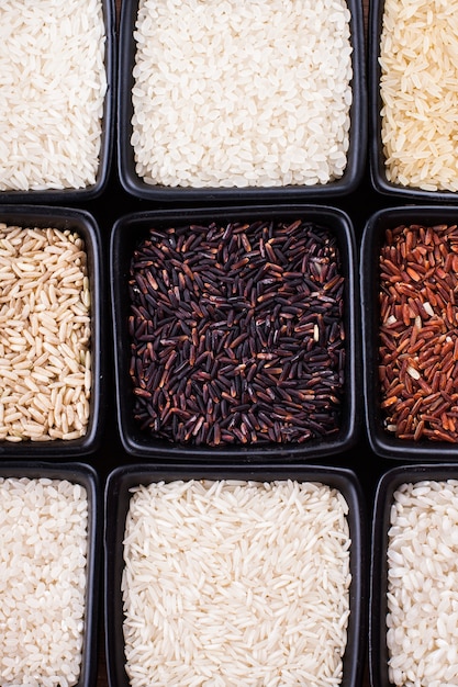 Différents types de riz dans des bols noirs se bouchent