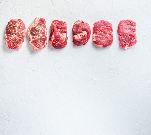 Différents types de steaks de boeuf cru sur un tableau blanc