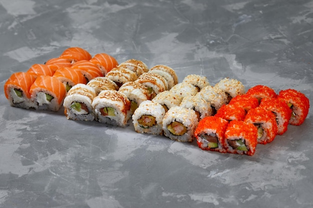 Différents types de sushis et de petits pains délicieux et juteux sur fond gris