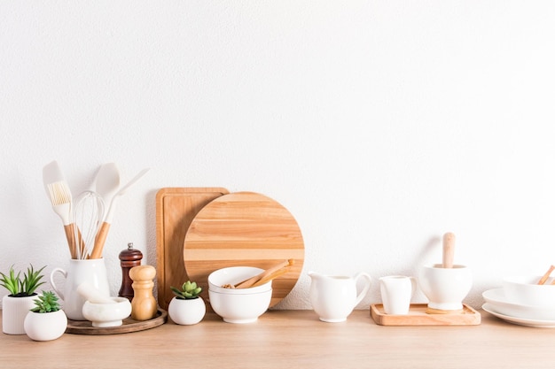 Différents types d'ustensiles de cuisine sur un comptoir en bois au mur de béton blanc texturé Concept zéro déchet respectueux de l'environnement