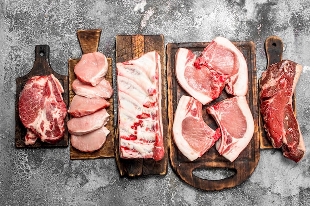 Différents types de viande crue sur les planches sur table rustique.