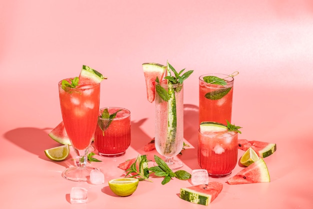 Différents verres élégants avec cocktail de pastèque Splash éclaboussure gouttes d'eau sur le fond rose avec la lumière du soleil