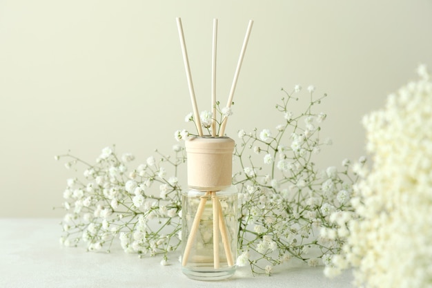 Diffuseur et fleurs sur table texturée blanche