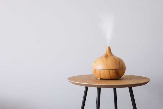 Diffuseur d'huile aromatique sur une table en bois sur fond blanc.