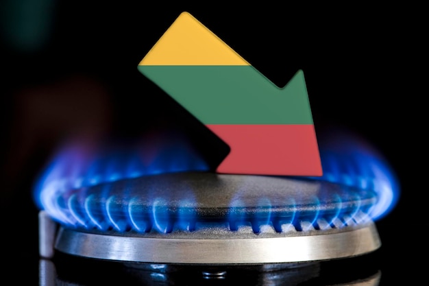 Diminution de l'approvisionnement en gaz en Lituanie Une cuisinière à gaz avec une flamme brûlante et une flèche aux couleurs du drapeau lituanien pointant vers le bas Concept de crise en hiver et manque de gaz naturel