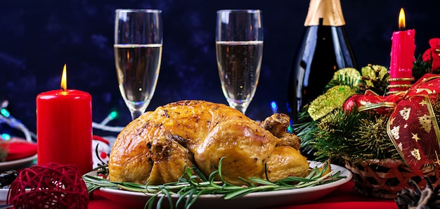 Dinde au four. Dîner de Noël. La table de Noël est servie avec une dinde, décorée de guirlandes lumineuses et de bougies. Poulet frit, table. Dîner de famille.