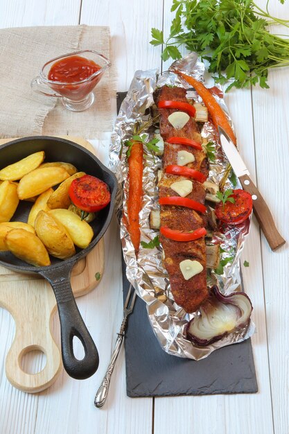 Dîner campagnard - côtelettes de veau rôties avec légumes et pommes de terre sur une table en bois blanc