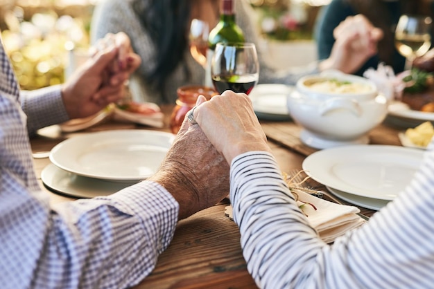 Dîner main dans la main et prière familiale à table pour la célébration de l'action de grâces avec la religion de la foi et la gratitude des vacances Amour social et tenue de la main des personnes priant pour la nourriture et le vin de fête