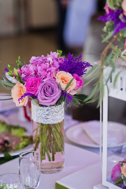 Dîner de mariage au restaurant, tables décorées de vases de roses.