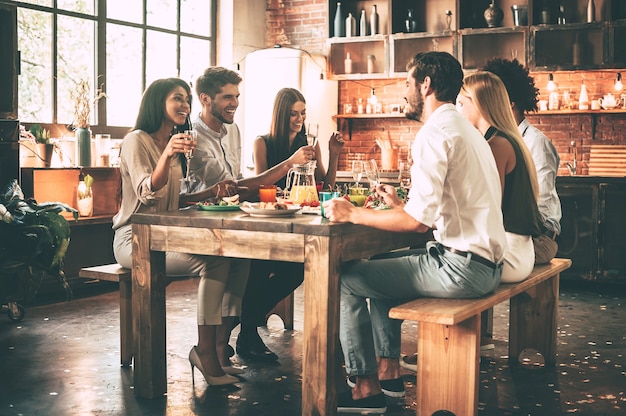 Dîner avec les meilleurs amis. Groupe de jeunes joyeux dînant assis ensemble dans la cuisine