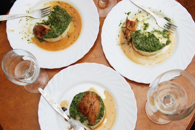 Dîner. Poitrine de poulet rôtie aux épinards et purée de pommes de terre sur table ronde avec verre à vin blanc.