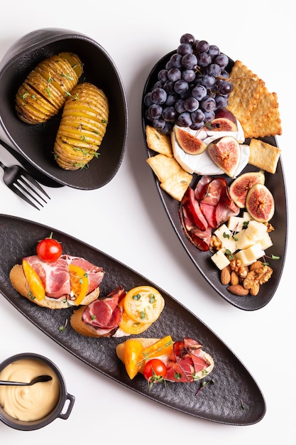 Dîner avec pommes de terre grillées et fromages assortis, prosciutto et fruits, bruschetta sur une assiette