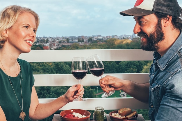 Dîner pour deux sur une terrasse privée au-dessus du vin d'Amsterdam acclamant et portant un toast couple d'amis heureux célébrant