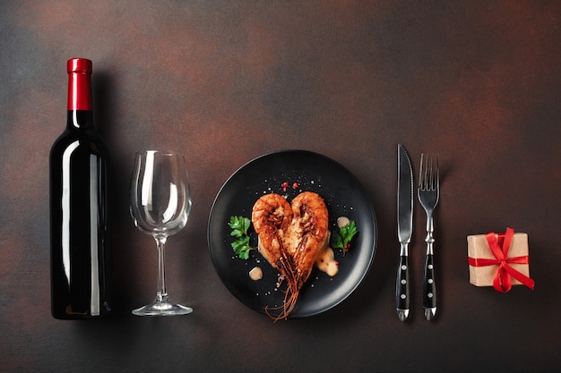 Dîner romantique avec des crevettes en forme de coeur et du vin sur un fond marron. Vue de dessus avec espace de copie