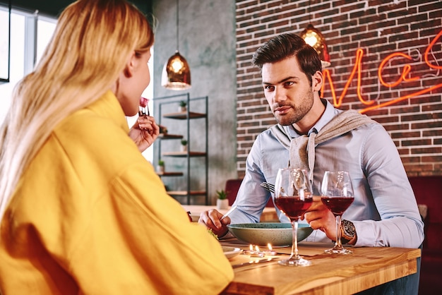 Dîner romantique homme en chemise bleue, manger et parler avec sa petite amie