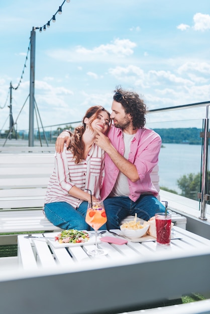 Dîner romantique. Joli couple à la mode ayant un merveilleux dîner romantique sur la terrasse avec vue sur la mer