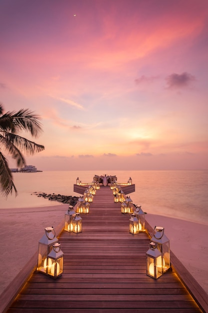 Dîner romantique sur la plage avec coucher de soleil, bougies avec des feuilles de palmier incroyables et ciel et mer au coucher du soleil