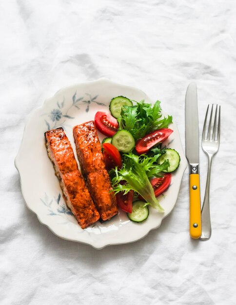 Dîner sain, sauce teriyaki, saumon au four et salade de légumes frais sur un fond clair.