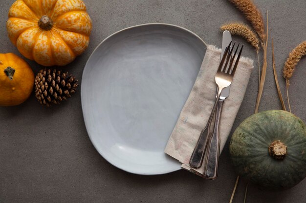 Dîner de thanksgiving d'automne au-dessus de la table avec des couverts de citrouilles et une assiette vide