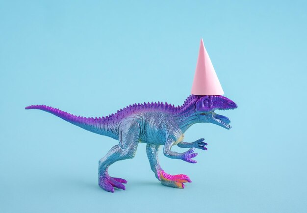 Photo dinosaure bleu mignon portant un chapeau de fête rose sur fond bleu idée drôle pour une carte d'anniversaire