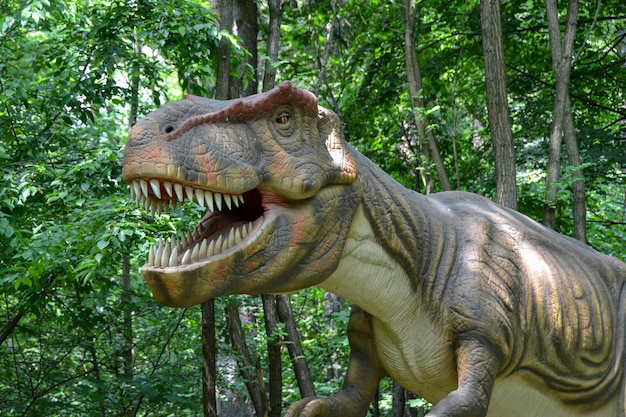 Un dinosaure avec une bouche ouverte se tient dans le contexte d'une forêt verte dense Lézards éteints