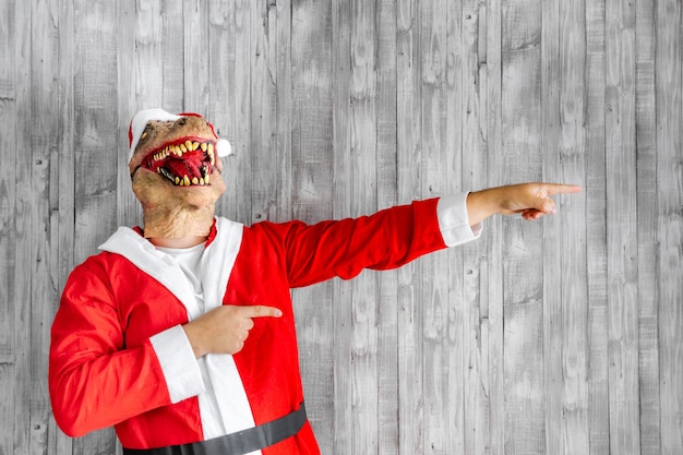 Dinosaure en costume de père Noël pointant du doigt vers la droite