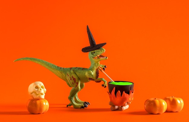 Un dinosaure portant un chapeau de sorcière prépare une potion dans un pot sur fond orange Carte de vœux d'Halloween
