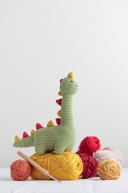 Dinosaure vert mignon au crochet avec un sceins d'un fil sur un fond blanc