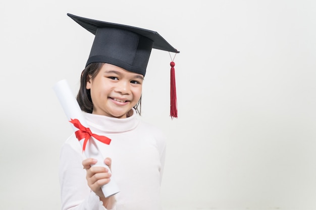 Photo diplômé de l'école asiatique heureux mignon avec un chapeau de graduation et un diplôme isolé sur fond blanc