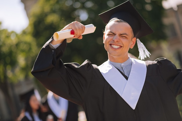 Photo diplômé excité levant la main avec un diplôme