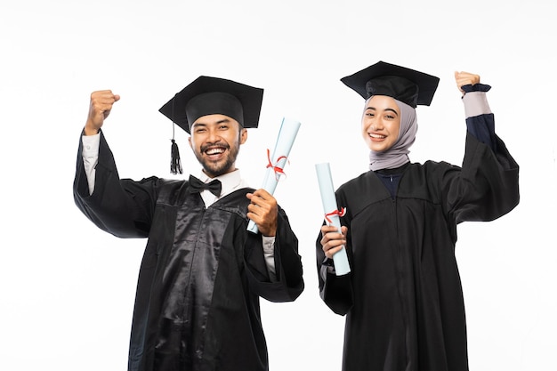 Diplômé excité portant une toge tenant un rouleau de papier de diplôme