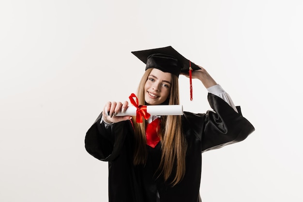 Diplôme de maîtrise avec ruban rouge dans les mains d'une fille diplômée en robe de graduation noire sur fond blanc Une fille diplômée termine ses études secondaires et célèbre la réussite scolaire